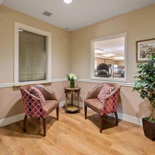 A cozy waiting area with two patterned chairs, a small table, and decorative plants.