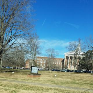 A view of a college campus with a clear blue sky and surrounding trees.