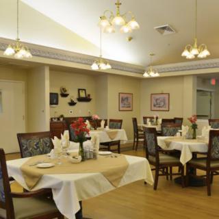 A well-decorated dining room with neatly arranged tables and chairs, featuring warm lighting.