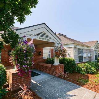 A charming building entrance adorned with floral arrangements and well-maintained landscaping.