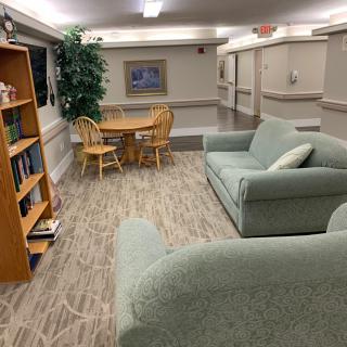A cozy common area with seating, bookshelves, and a dining table.