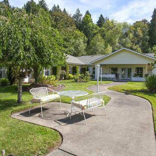 A charming house with a well-maintained garden and patio furniture along a curved pathway.