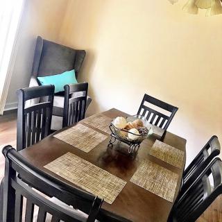A cozy dining room with a wooden table set for a meal, featuring neatly arranged placemats and comfortable chairs.