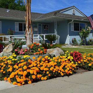 A charming house with a beautifully landscaped front yard filled with vibrant flowers.