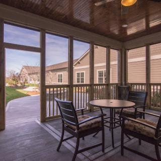 A cozy screened porch with a table and chairs, providing a relaxing view of the outdoors.