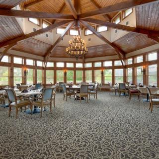 A spacious and elegant restaurant interior with a wooden ceiling and large windows.