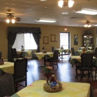 A neatly arranged dining area with tables and chairs, featuring soft lighting and decorative elements.