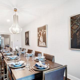 A modern dining room with an elegantly set table and contemporary artwork on the walls.