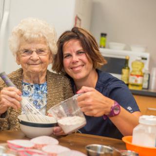 A joyful moment in the kitchen, as a caregiver and an elderly person bond over baking.