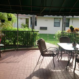 A cozy patio with a table and chairs under a canopy, overlooking a garden.