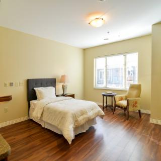 A bright and cozy bedroom with a single bed, chair, and window.