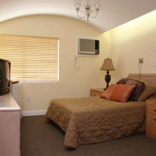 A cozy hotel bedroom with a bed, TV, and lamp.