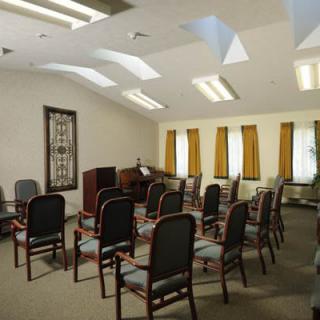 A small conference room with arranged chairs and a piano near the windows.