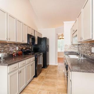A modern kitchen with white cabinets, dark countertops, and stainless steel appliances.