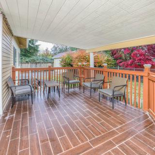 A covered wooden deck with outdoor seating and a table, surrounded by a backyard garden.