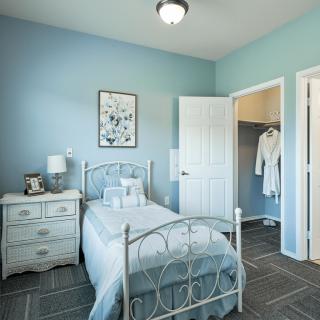 A cozy bedroom with blue walls, featuring a single bed and a nightstand.