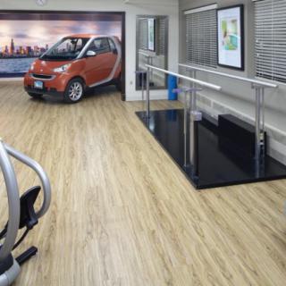 A modern rehabilitation center featuring a small car, exercise equipment, and wooden flooring.