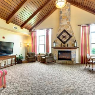 A spacious living room with high ceilings and a stone fireplace, featuring comfortable seating and large windows.