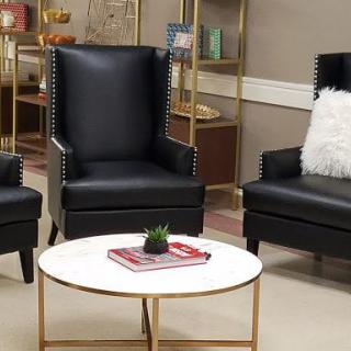 A modern lounge area with black armchairs and a white round coffee table.
