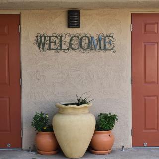 A welcoming entrance with decorative potted plants and a 'Welcome' sign between two doors.