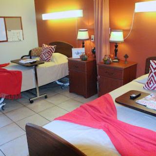 A well-organized patient room featuring two beds, bedside tables, and warm lighting.