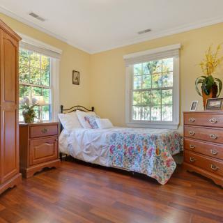 A cozy bedroom with wooden furniture and bright natural lighting.