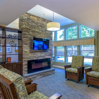 A modern living room with a stone fireplace, mounted television, and comfortable seating area.