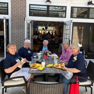 A group of seniors enjoying a meal together at an outdoor restaurant setting.