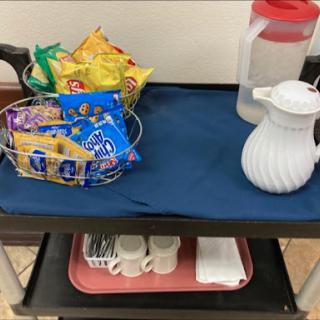 A serving cart with a variety of snacks and a pitcher of water.