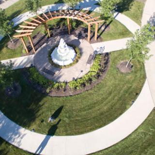 A serene aerial view of a park featuring a fountain surrounded by pathways and lush greenery.