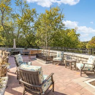 A spacious outdoor patio with comfortable seating, surrounded by trees and under a clear blue sky.