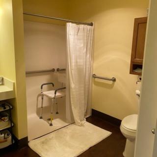 An accessible bathroom featuring a shower with grab bars and a shower chair.