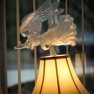 A beautifully crafted lamp featuring a glass eagle sculpture perched on its shade.