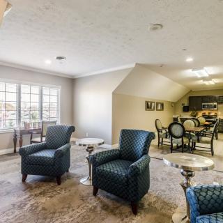 A spacious living room with plush armchairs, a dining area in the background, and natural light streaming through large windows.