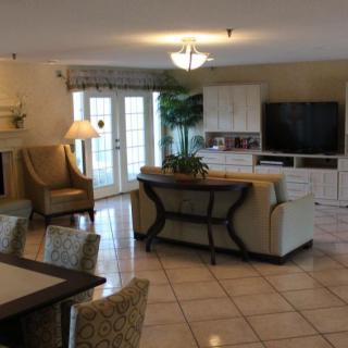 A spacious and elegantly decorated living room featuring comfortable seating, a dining area, and a large TV.