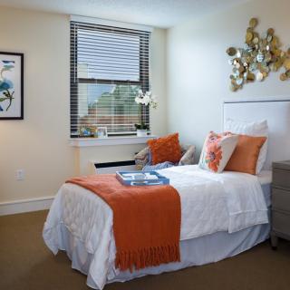 A cozy bedroom with orange accents and modern decor.