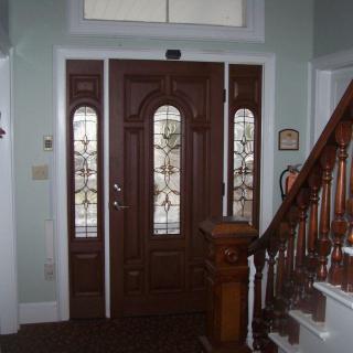 A wooden entry door with stained glass panels next to a staircase.