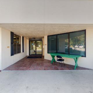 An entrance featuring large glass doors and a distinct green table, welcoming visitors.