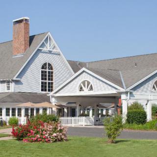 A large residential house with a landscaped garden under a clear blue sky.