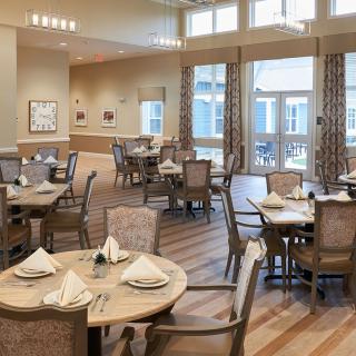A spacious dining room with elegantly set tables and large windows.