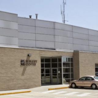 A government building with a parking lot and a vehicle parked in front.