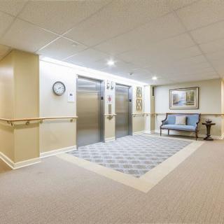 A modern lobby area with two elevators, comfortable seating, and warm lighting.