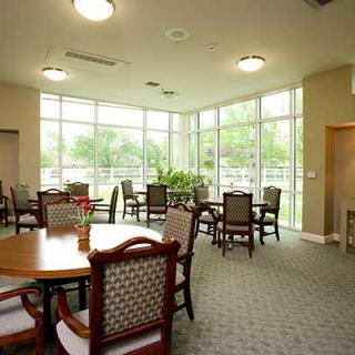 A well-lit dining area featuring several tables and chairs, with large windows allowing natural light to fill the room.
