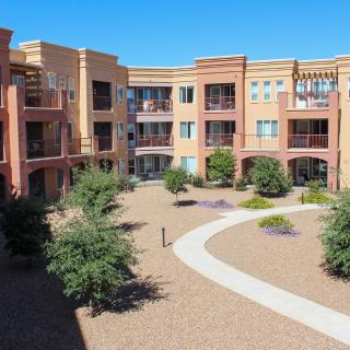 A modern apartment complex with desert landscaping and a winding pathway.