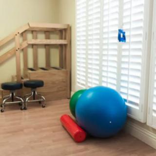 A rehabilitation room with therapy balls and stools.
