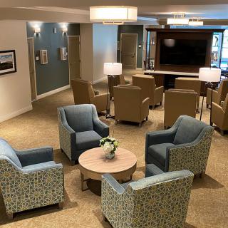 A modern lobby seating area with comfortable chairs, a table, and a television.