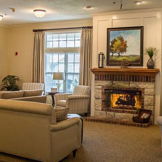 A cozy living room featuring a warm fireplace, comfortable seating, and a large window.