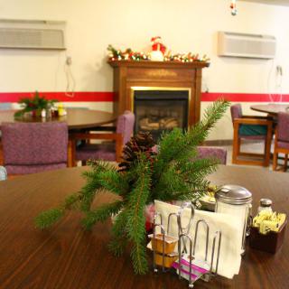 A cozy dining area with a decorated table and a fireplace in the background.