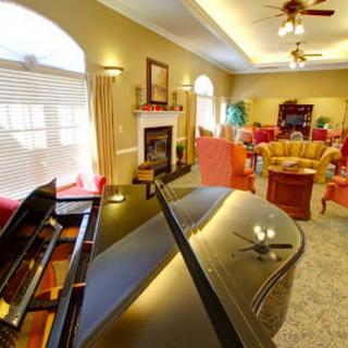 A cozy living room featuring a grand piano, fireplace, and comfortable seating area.