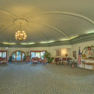 A spacious, elegantly decorated room featuring a large chandelier and arched windows.